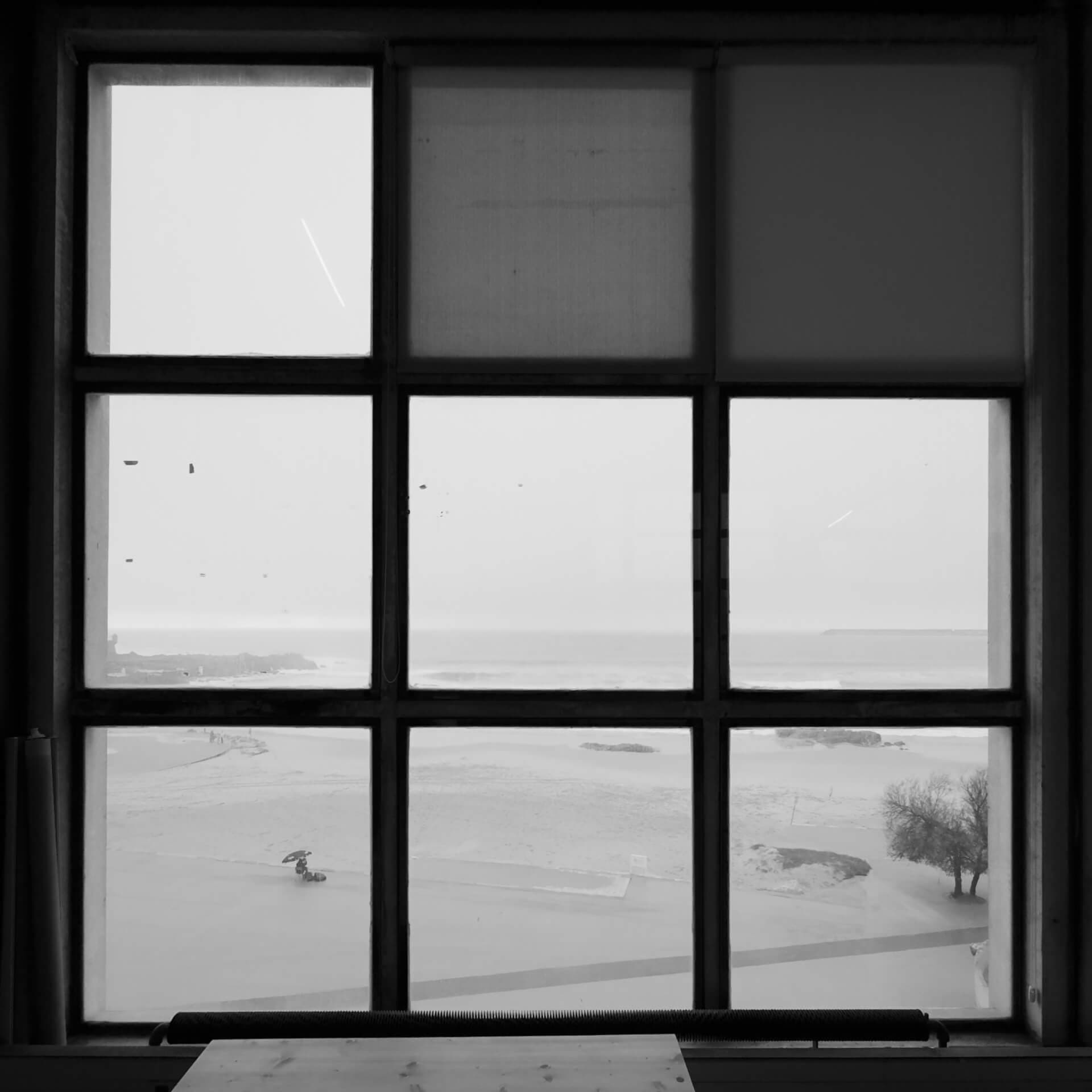 Beach and ocean seen through an open window in black and white