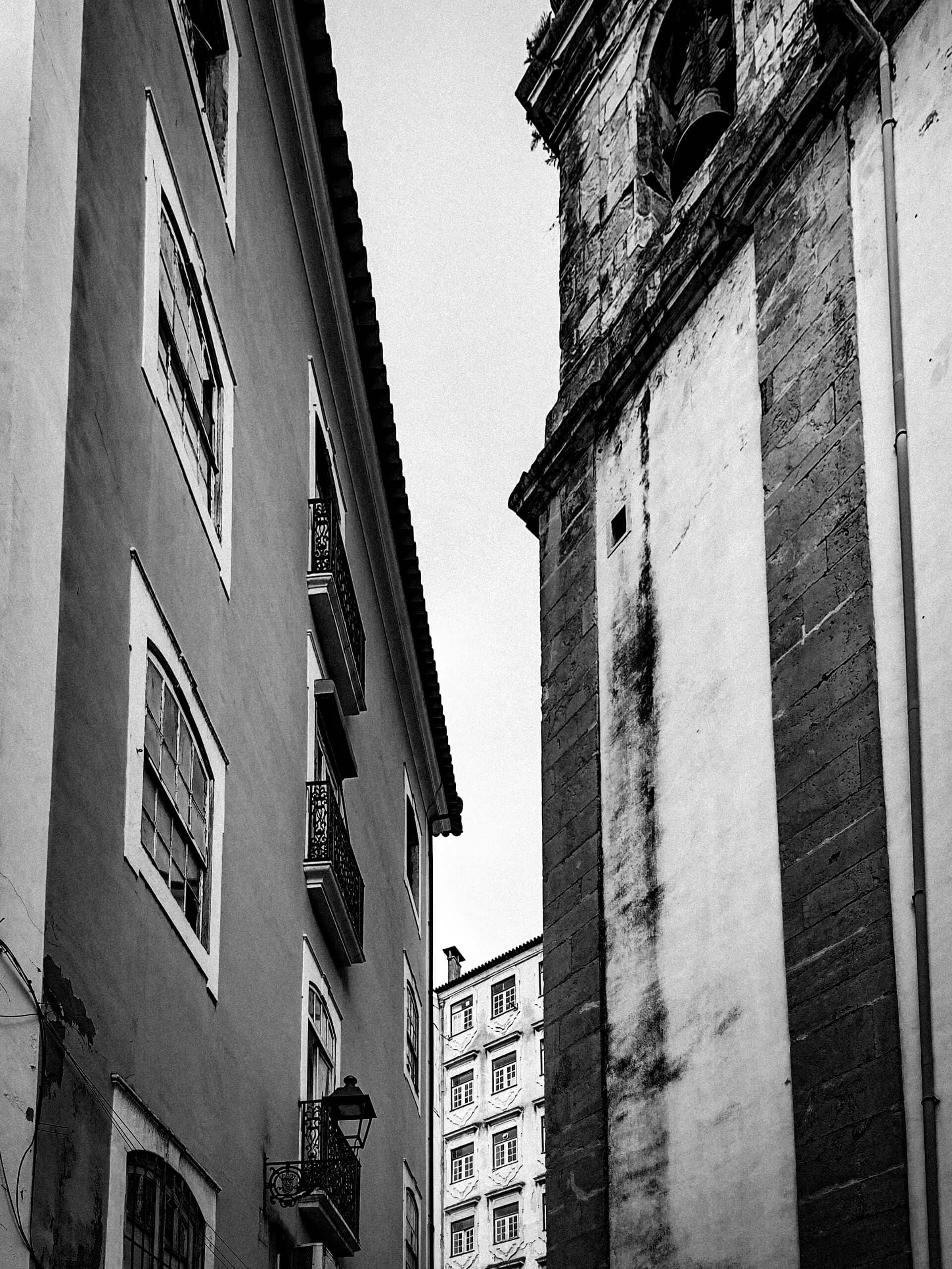 Narrow alley leading to a church tower in black and white