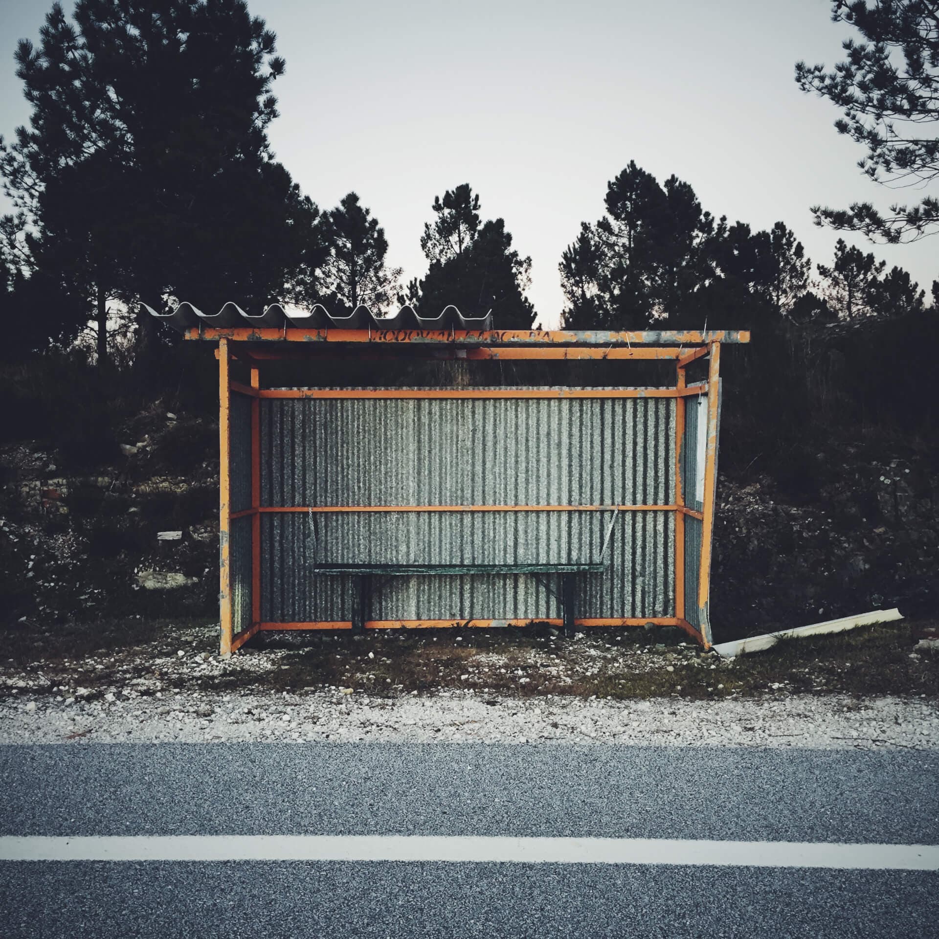 Weathered rural bus stop with a corrugated metal roof