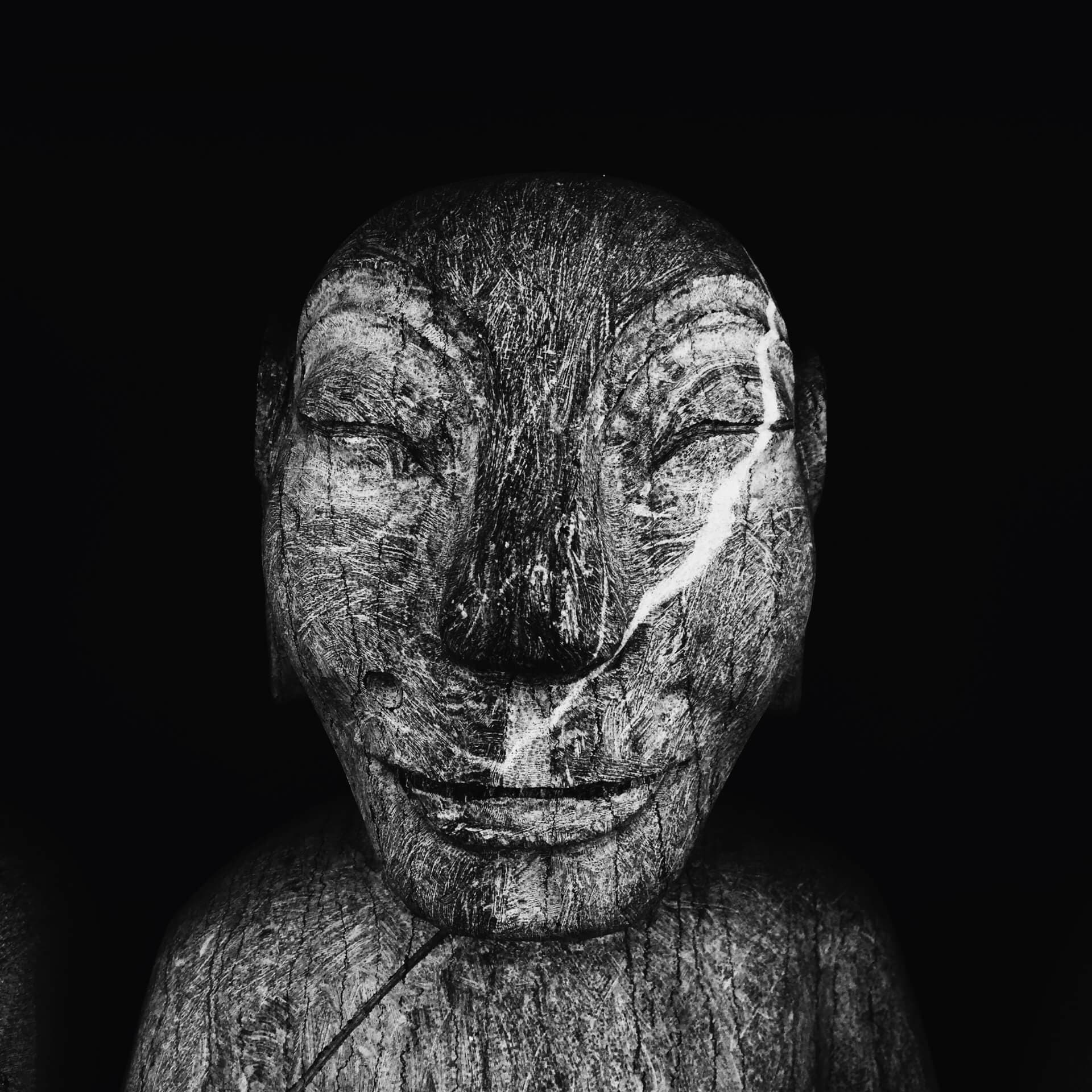 Weathered wooden face sculpture in black and white