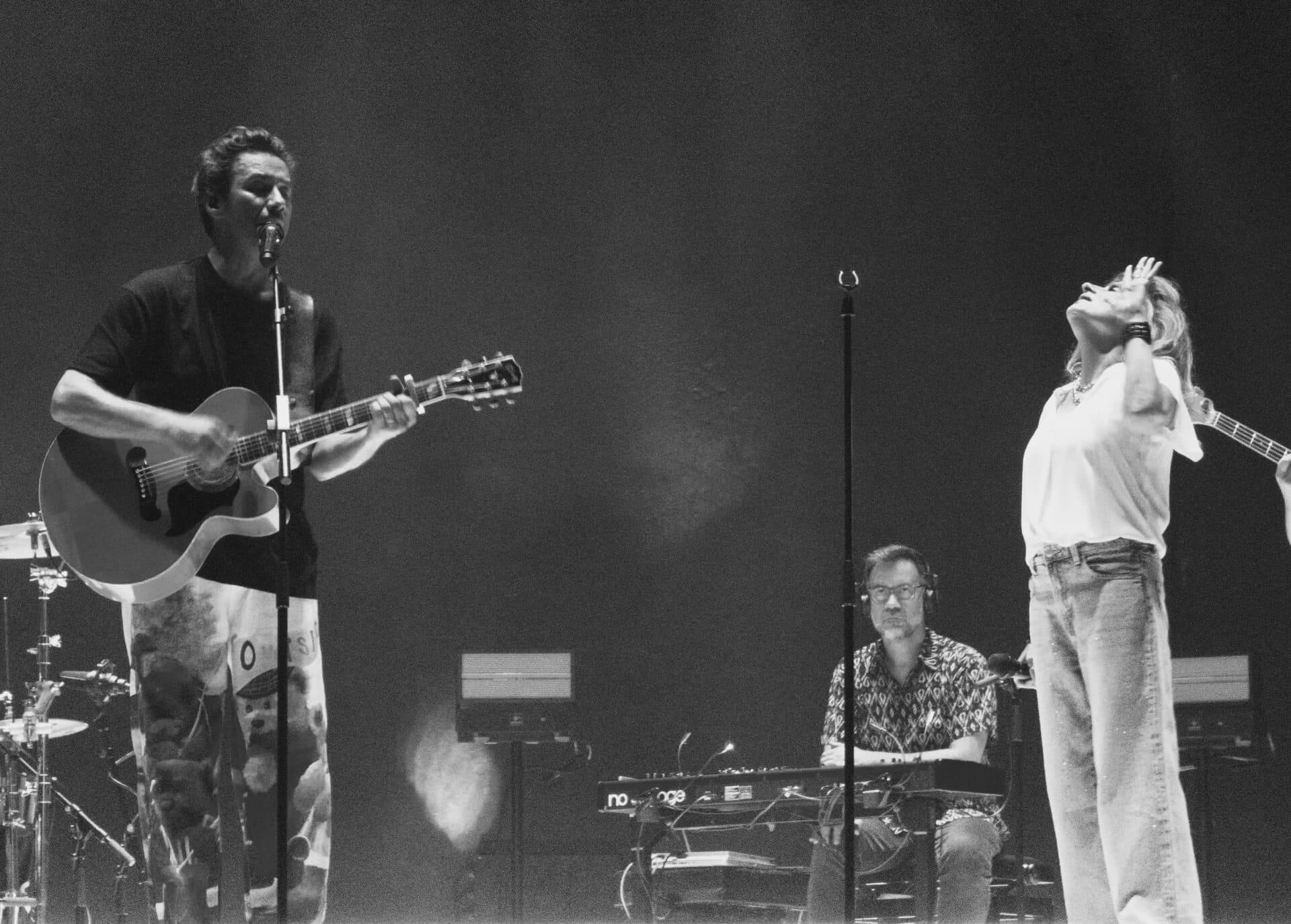 Band performing live on stage with dramatic lighting in black and white