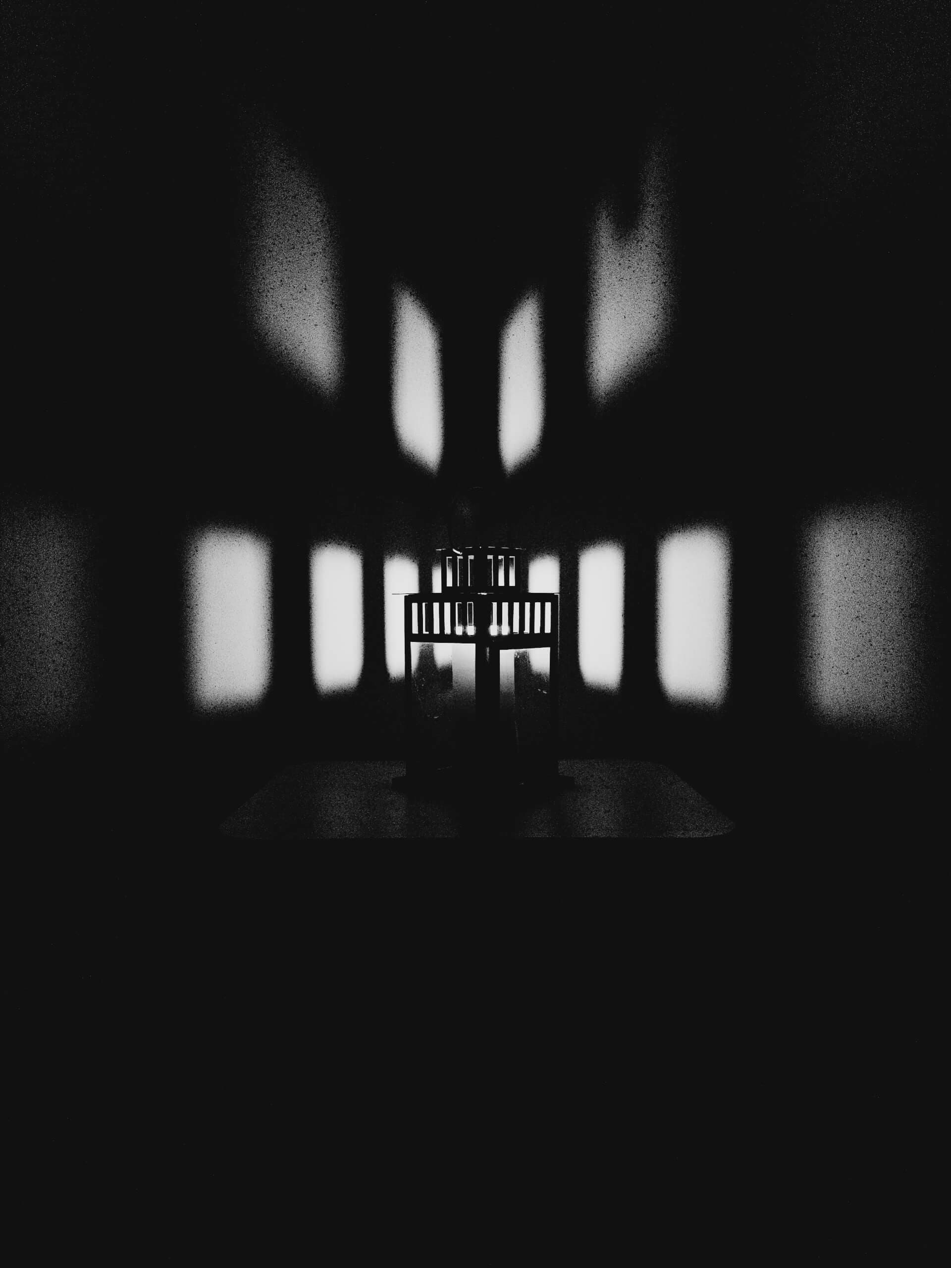Chair silhouette seen through a window with soft light patterns