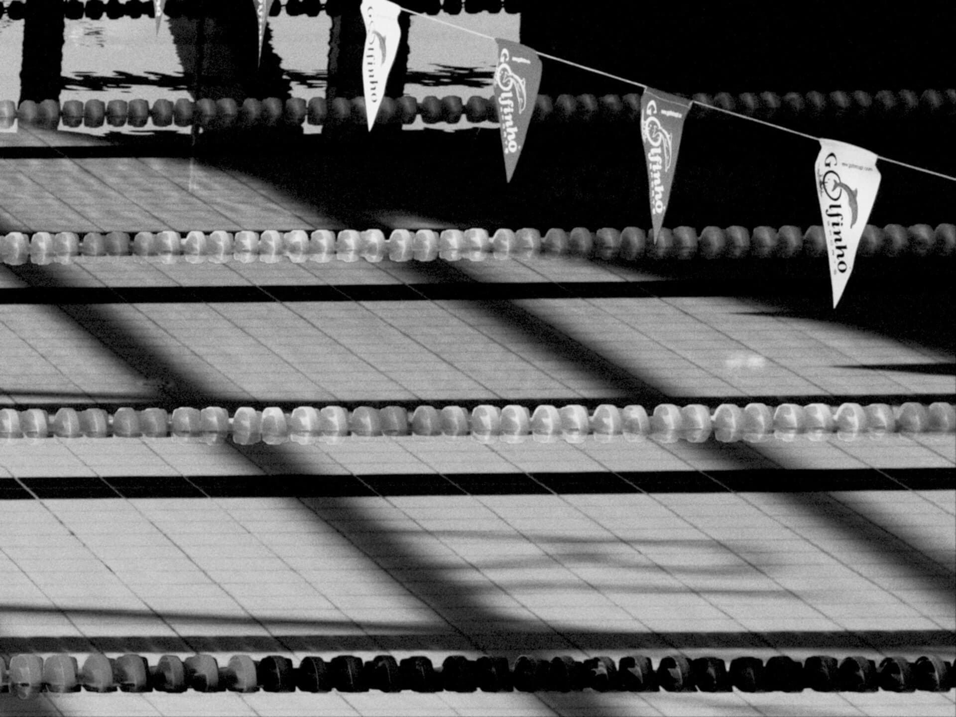 Swimming pool lanes with colorful pennant flags overhead in black and white