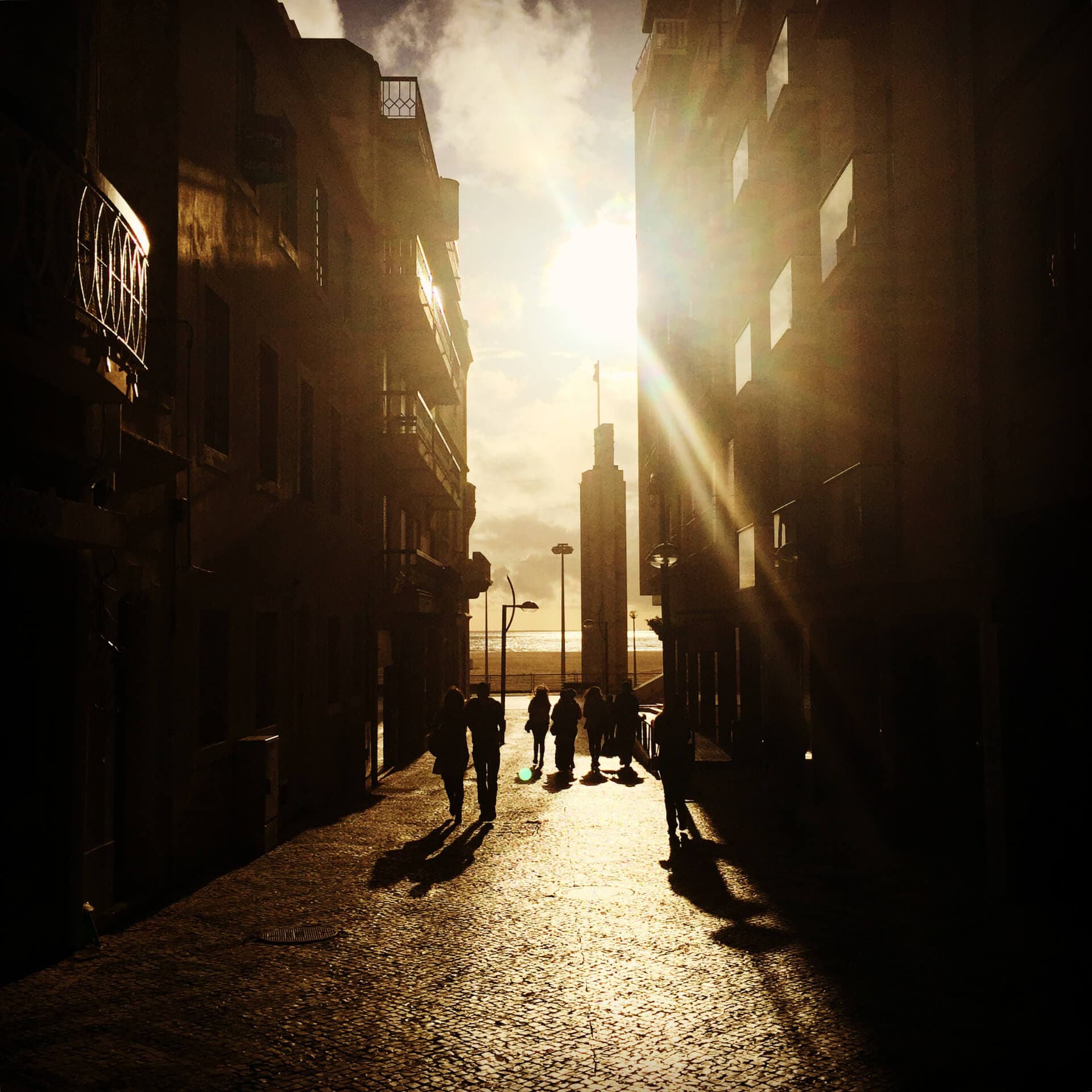 Golden sunset light through a narrow street with silhouetted figures