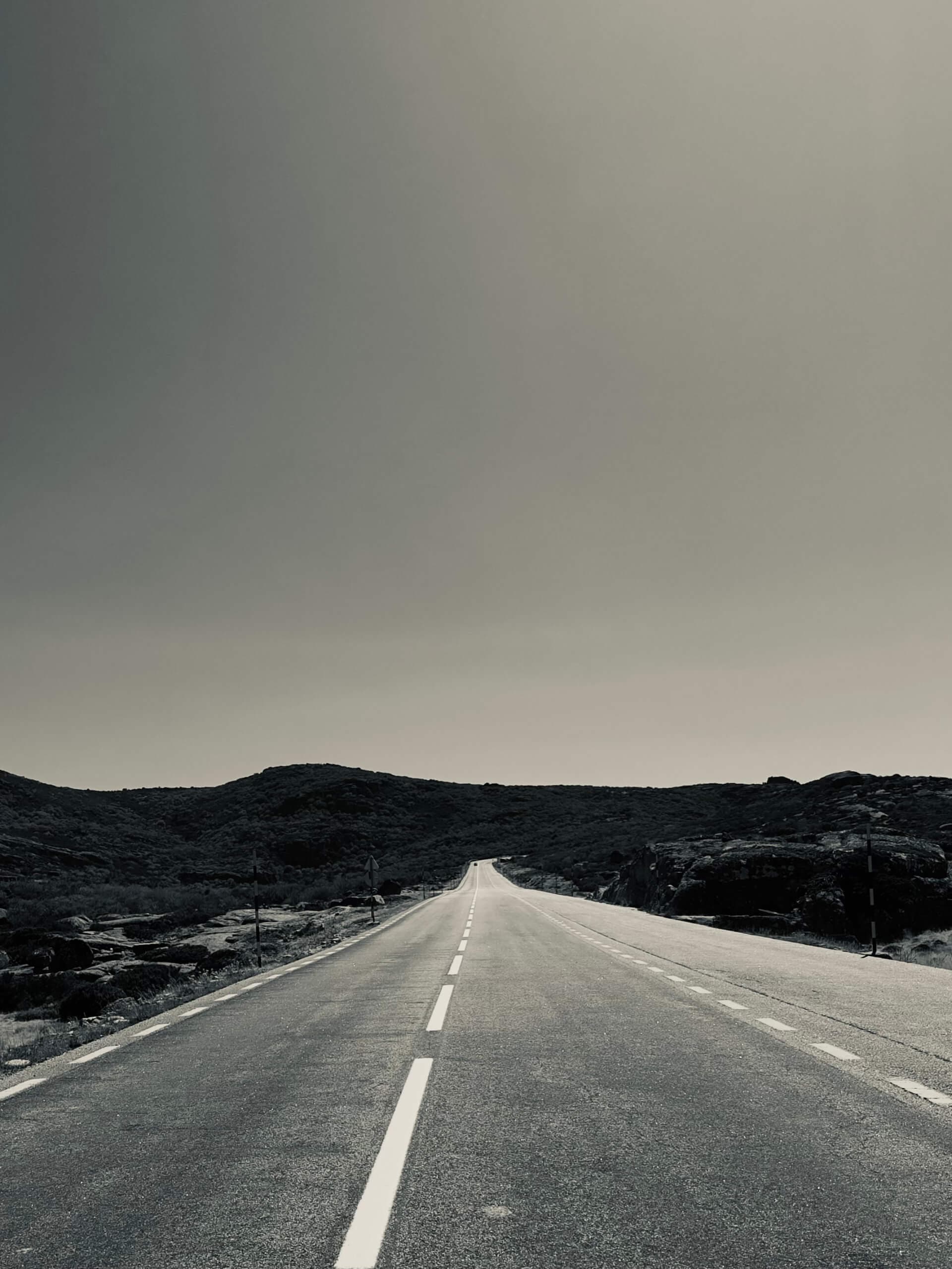 Empty road stretching to the horizon through barren hills