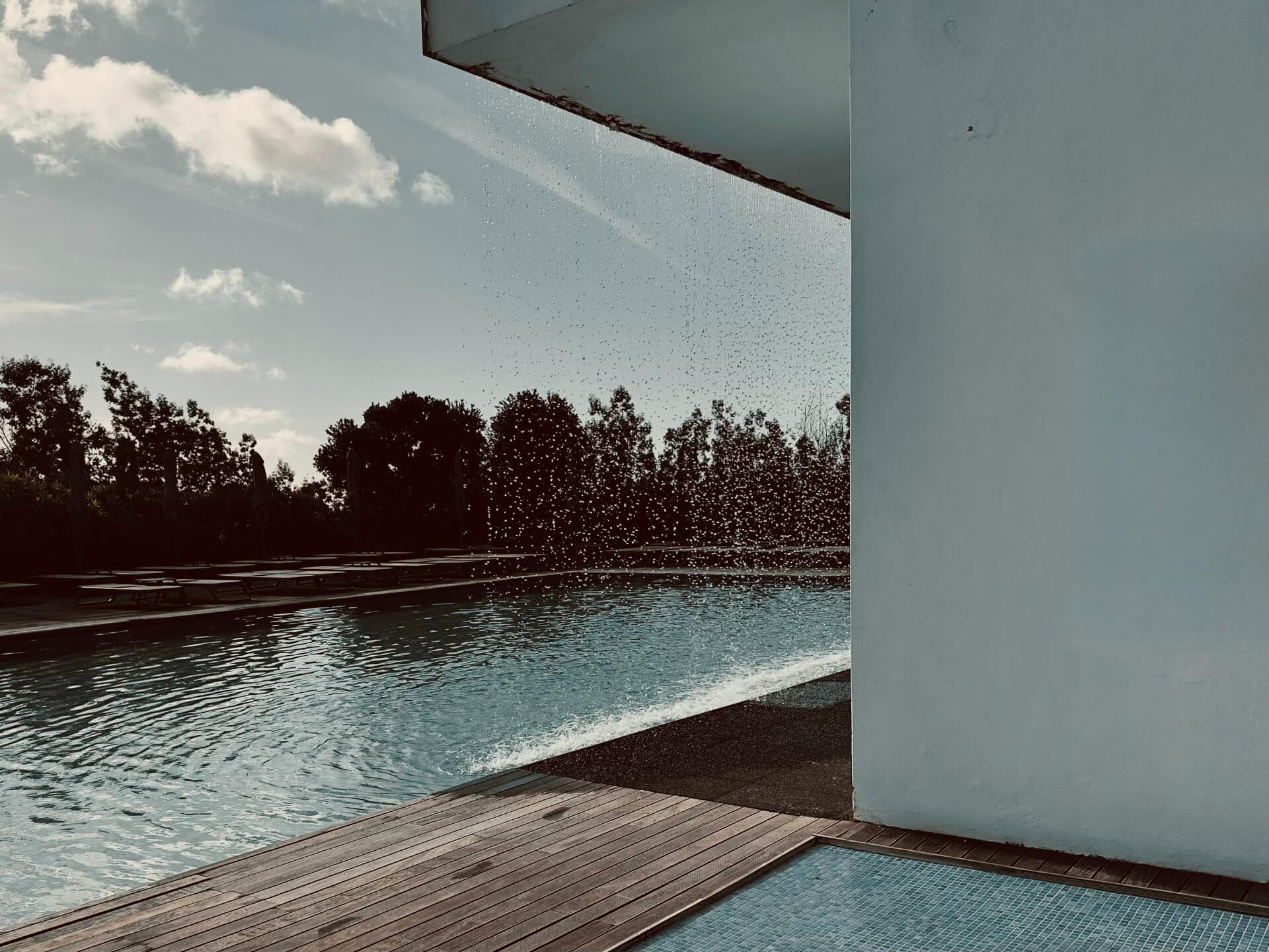 Swimming pool with a water curtain feature and wooden deck